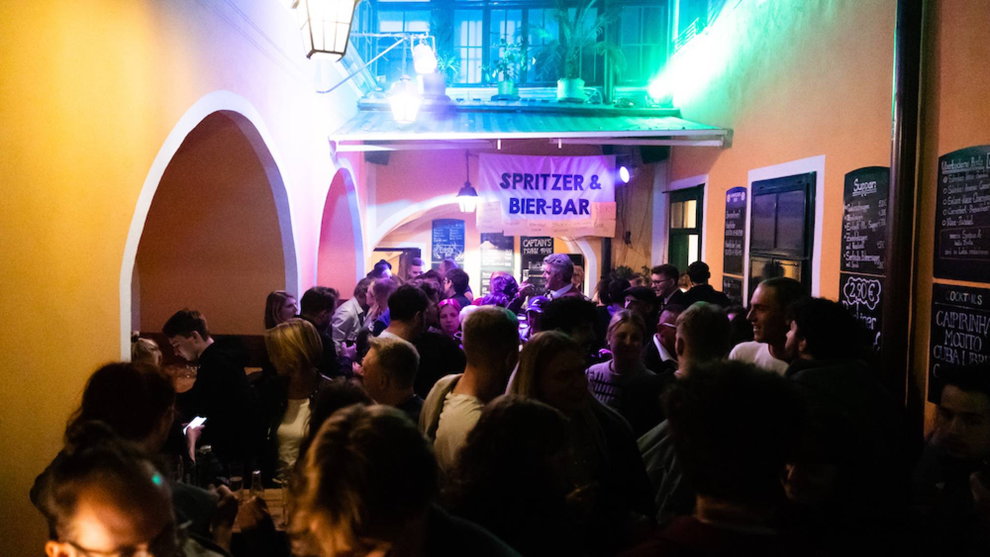 Zahlreiche Menschen stehen abends vor dem Weinlokal Vino in der schön beleuchteten St. Pöltner Innenstadt. Foto: Patrick Salfinger Fotografie
